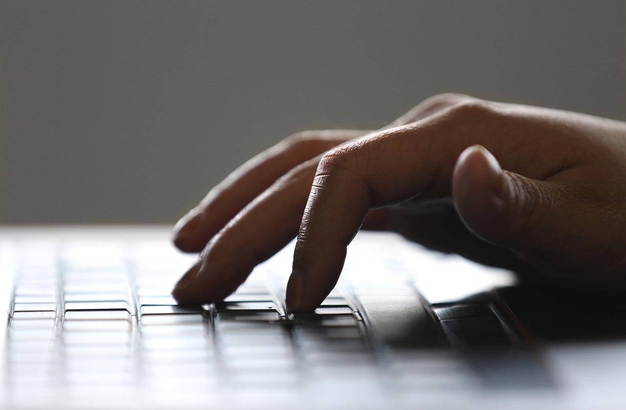 fingers typing on a black laptop keyboard